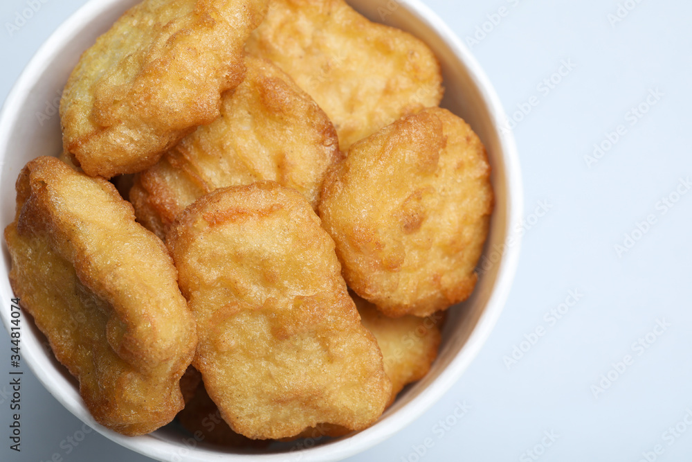 Bucket with delicious chicken nuggets on light background, closeup Bucket with delicious chicken nuggets on light background, closeup