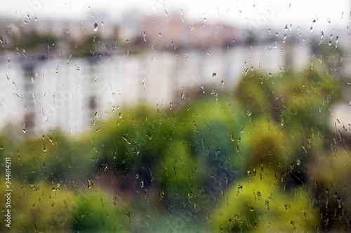 Close-up shot of rain drops on the window with blurred spring city landscape © Diana Vyshniakova