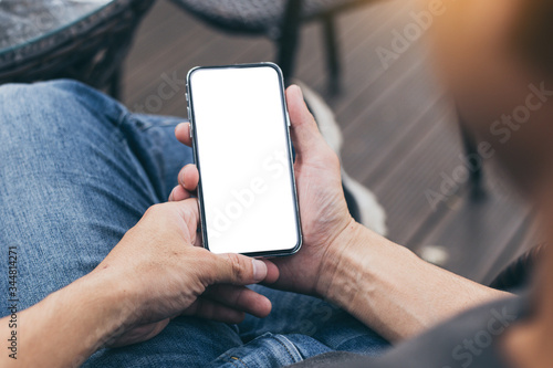 cell phone Mockup image blank white screen.man hand holding texting using mobile on desk at coffee shop.background empty space for advertise.work people contact marketing business,technology © panitan