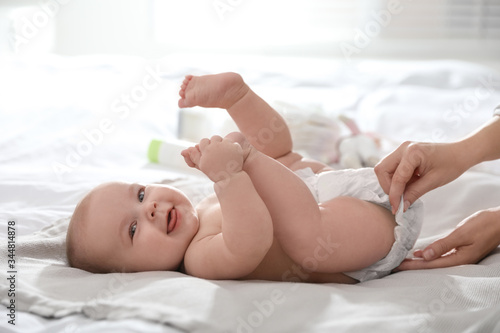 Mother changing her baby's diaper on bed photo
