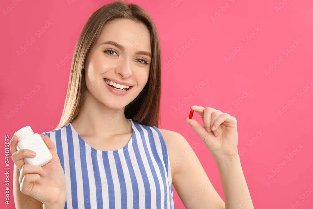 Young woman with vitamin pill on pink background Young woman with vitamin pill on pink background