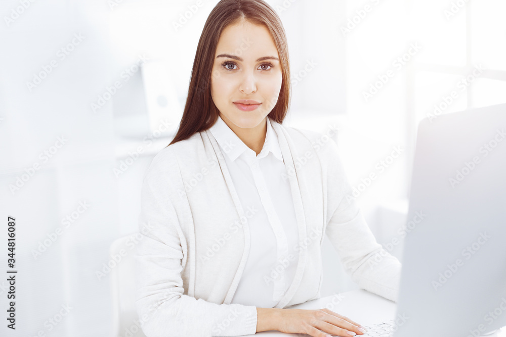 Business woman sitting and working with computer in white office. Student girl studying or secretary making report. Success concept Business woman sitting and working with computer in white office. Student girl studying or secretary making report. Success concept