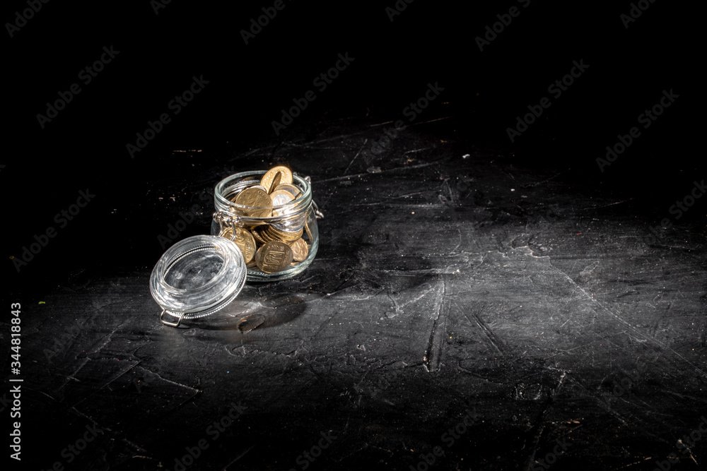 Coins in money jar on dark background. Saving money concept for life, future, education