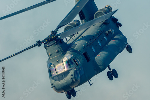 Fototapeta Naklejka Na Ścianę i Meble -  Military combat and war with Chinook helicopter close up flying through the chaos. Military concept of power, force, strength, air raid.