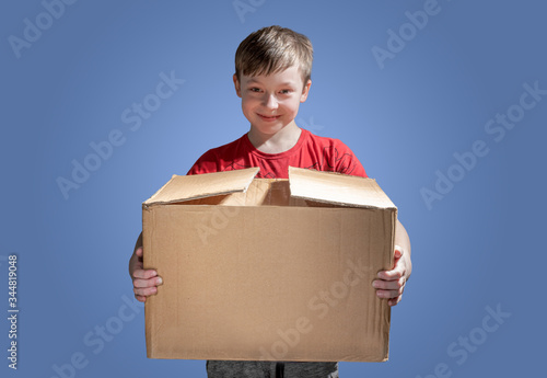 Tablou pe pânză Boy holding a cardboard box on dark background
