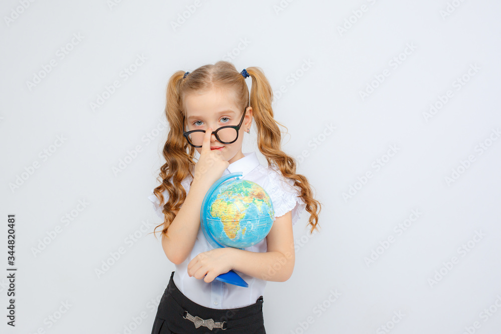 a little girl in school uniform and glasses holds a globe in her hands on a white background a little girl in school uniform and glasses holds a globe in her hands on a white background