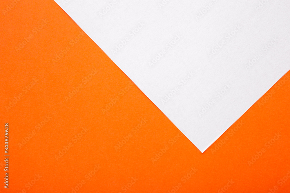 Orange and white paper as background. Two colored bright paper texture, top view with place for text