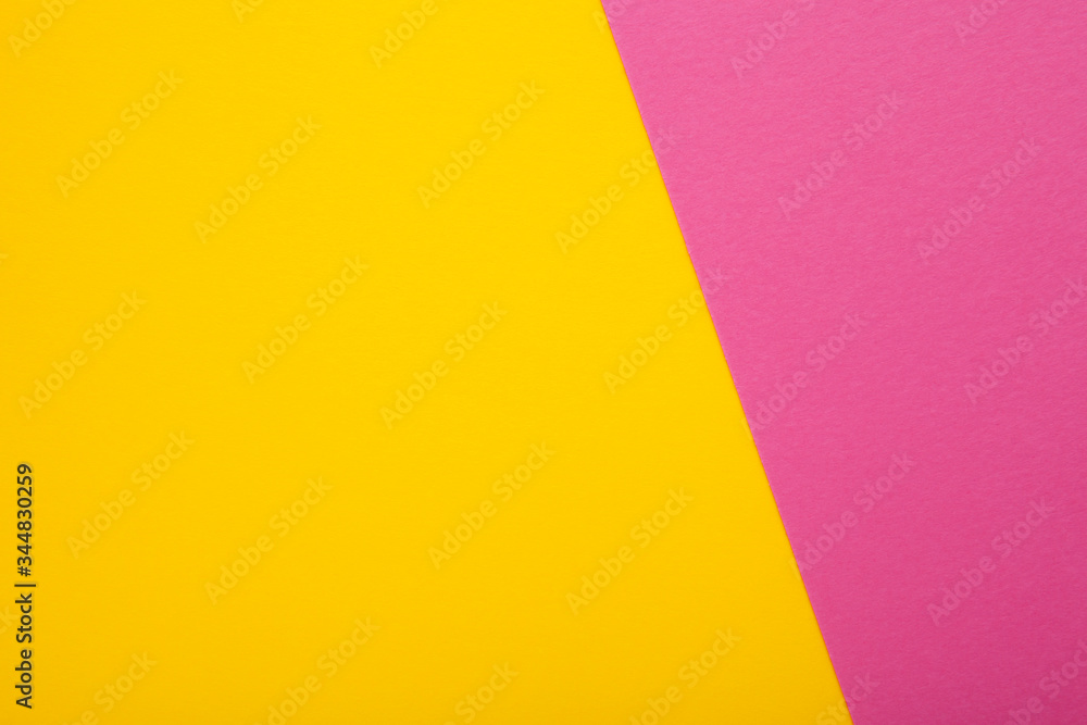 Pink and yellow paper as background. Two colored bright paper texture, top view with place for text