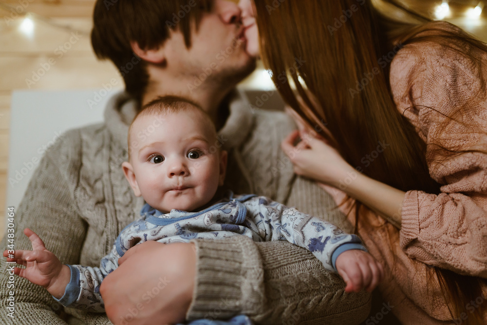 traditional married couple with a baby in the arms of a dad kissing on the lips of the baby mom traditional married couple with a baby in the arms of a dad kissing on the lips of the baby mom