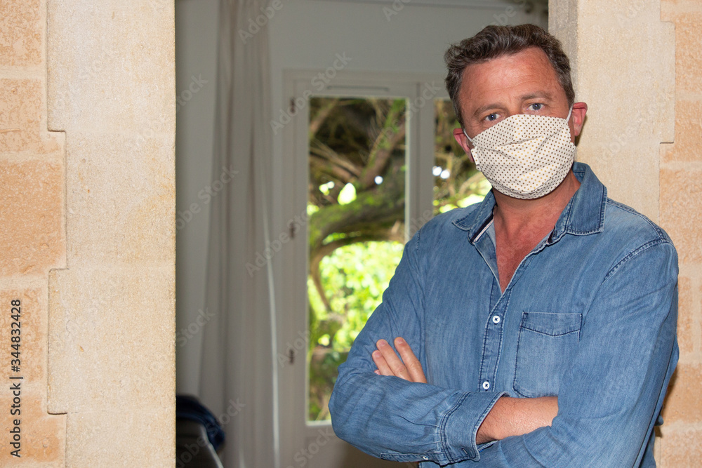 man wearing protective medical face mask with arms crossed at home in Contagious disease preventive measures coronavirus COVID-19 man wearing protective medical face mask with arms crossed at home in Contagious disease preventive measures coronavirus COVID-19