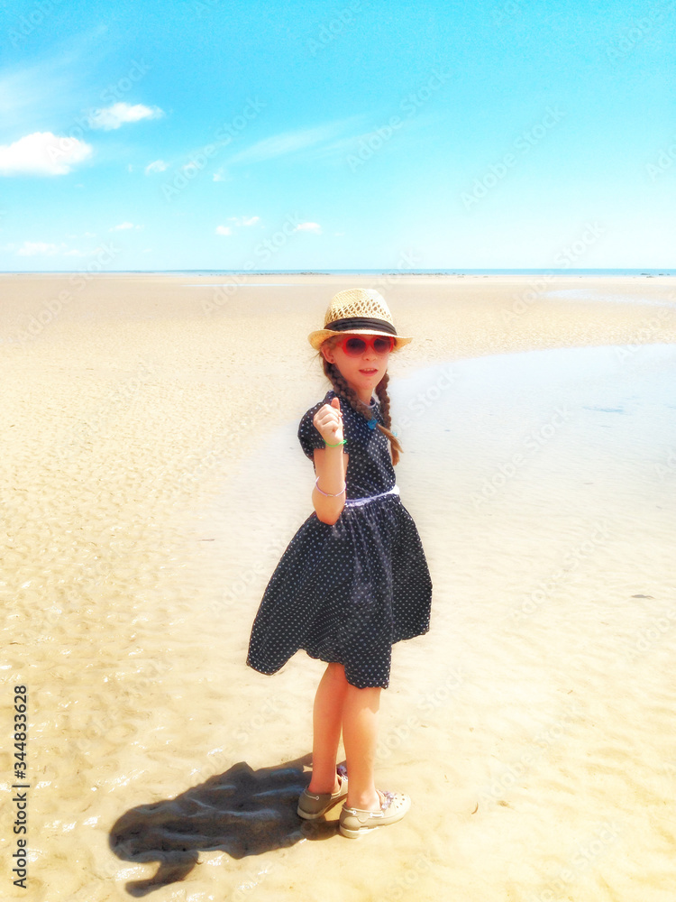 Young girl in a dress and hat at the beach