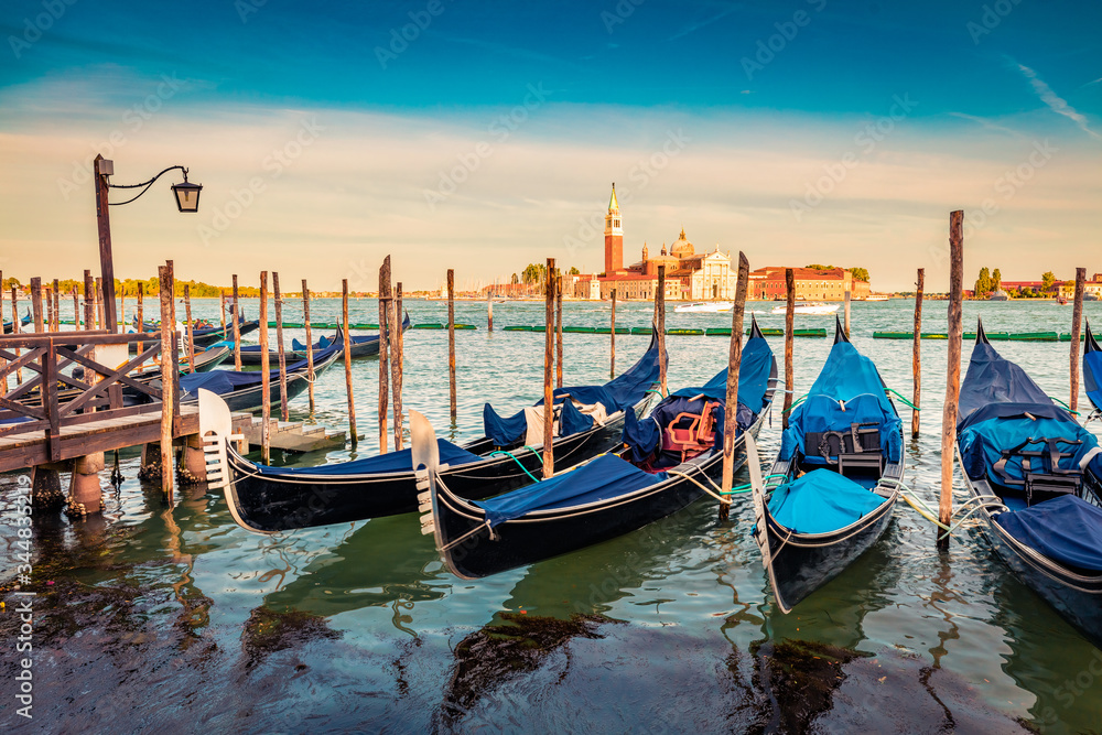 Picturesque summer view of the gondolas parked beside the Riva degli Schiavoni in Venice, Italy, Europe. Splendid Mediterranean scene wit Church of San Giorgio Maggiore on background.