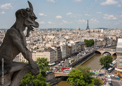 Gothic chimera on Paris' Notre Dame cathedral looks over the city - views of Eiffel Tower, River Seine and Les Invalides