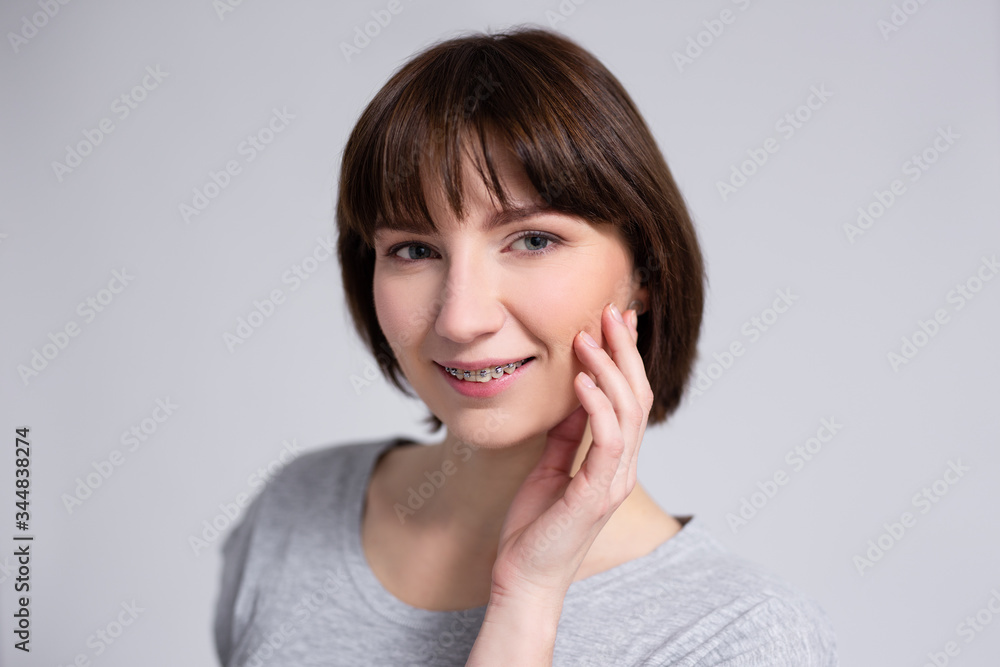 smiling woman with braces on teeth over gray background smiling woman with braces on teeth over gray background