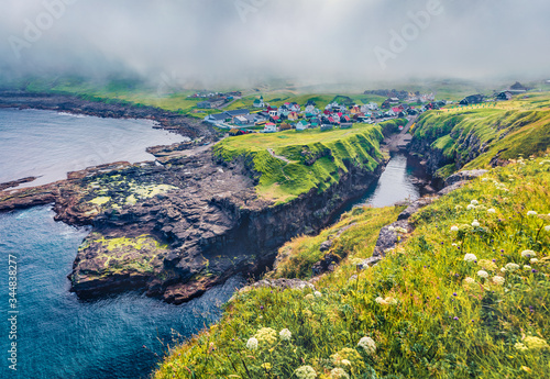 Exciting morning view of Gjogv village. Misty summer scene of Eysturoy island. Bright panoramic seascape of Atlantic ocean, Faroe Islands, Kingdom of Denmark, Europe.