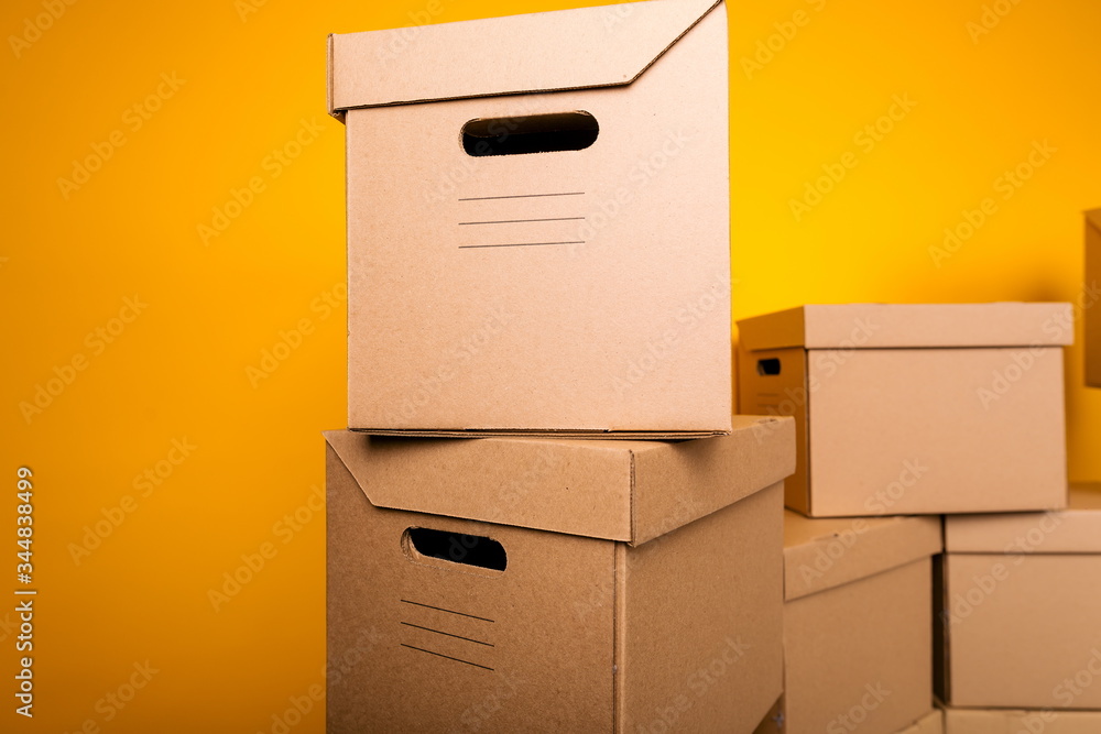Cardboard boxes for moving to another apartment on a yellow background close up Cardboard boxes for moving to another apartment on a yellow background close up