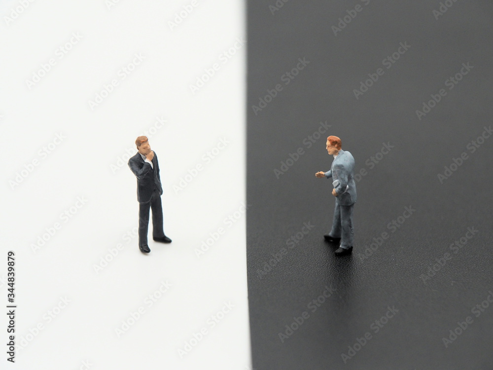 A miniature businessman on white background and a miniature businessman on black background.Debate concept image. A miniature businessman on white background and a miniature businessman on black background.Debate concept image.