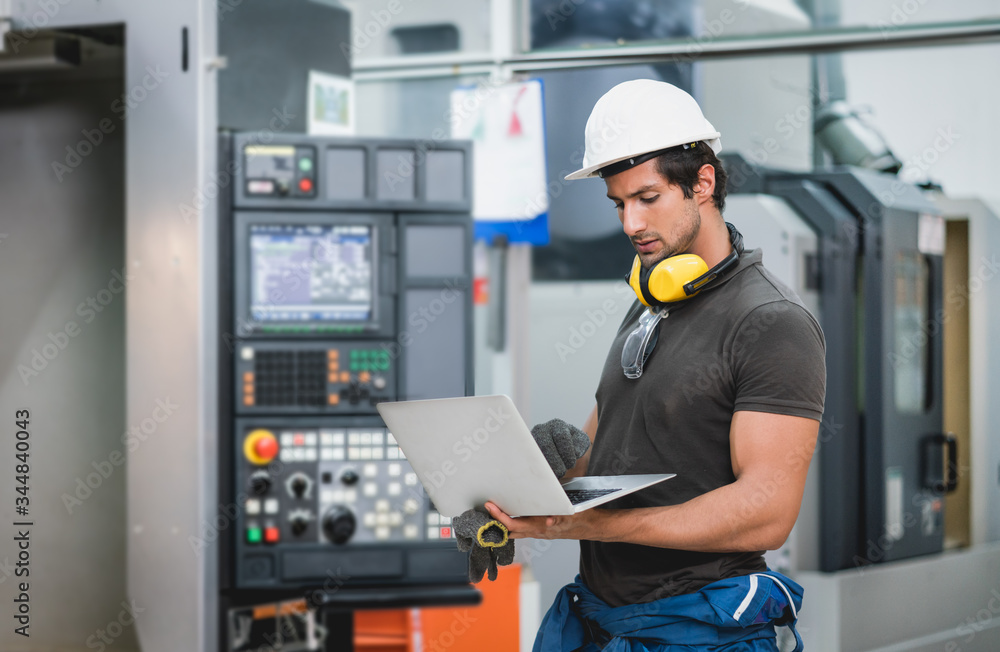 Engineer using laptop computer operating control CNC Machinery at factory Industrial Engineer using laptop computer operating control CNC Machinery at factory Industrial