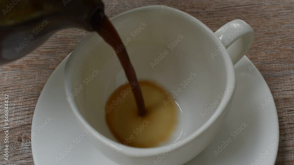 black coffee pouring from jar to cup on table black coffee pouring from jar to cup on table