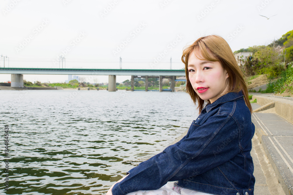 多摩川の岸辺に座る女性