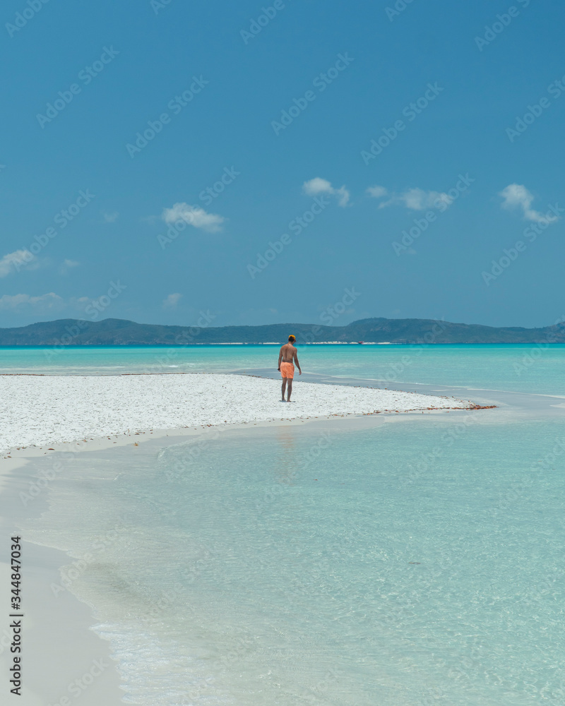 Man on paradise blue beach. Tourist on Whitsundays beach, white sand, in orange shorts, hat with aqua turquoise ocean. Travel, beauty, holiday, vacation, exotic. Whitsundays Islands, Australia. Man on paradise blue beach. Tourist on Whitsundays beach, white sand, in orange shorts, hat with aqua turquoise ocean. Travel, beauty, holiday, vacation, exotic. Whitsundays Islands, Australia.