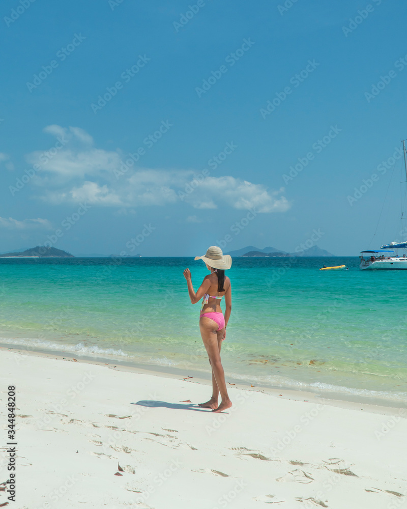Woman on paradise blue beach. Tourist on Whitsundays beach, white sand, in pink bikini & hat, with aqua turquoise ocean. Travel, holiday, vacation, paradise, exotic. Whitsundays Islands, Australia. Woman on paradise blue beach. Tourist on Whitsundays beach, white sand, in pink bikini & hat, with aqua turquoise ocean. Travel, holiday, vacation, paradise, exotic. Whitsundays Islands, Australia.