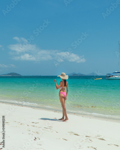 Woman on paradise blue beach. Tourist on Whitsundays beach, white sand, in pink bikini & hat, with aqua turquoise ocean. Travel, holiday, vacation, paradise, exotic. Whitsundays Islands, Australia.