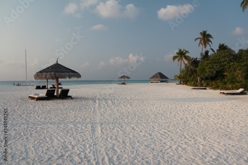 Transats et parasol sur plage de sable blanc
