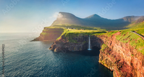 Fototapeta Naklejka Na Ścianę i Meble -  View from flying drone. Majestic morning scene of Mulafossur Waterfall. Stunning summer view of Vagar island, Faroe Islands,  Denmark, Europe. Beauty of nature concept background.
