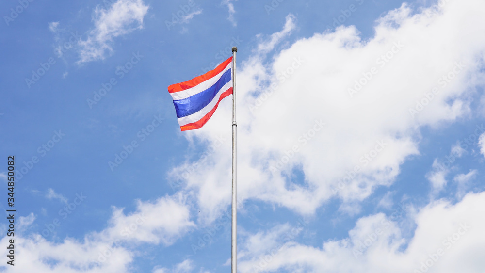 Thai national flag on blue sky background.