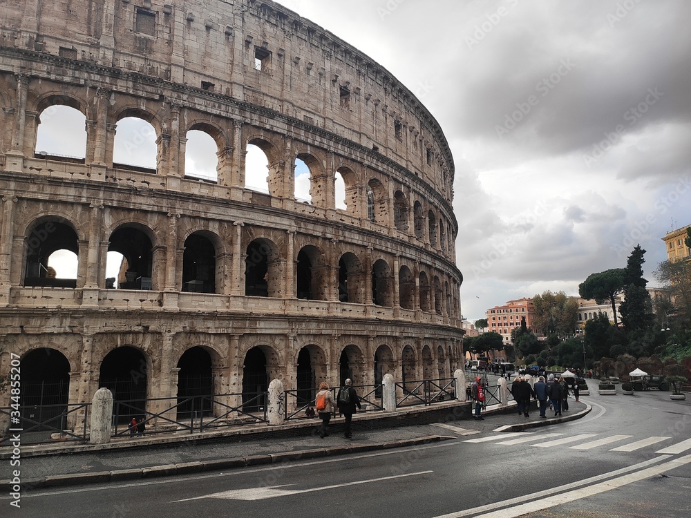 Tourists walking around Coliseum, Rome, Italy, in a stormy day