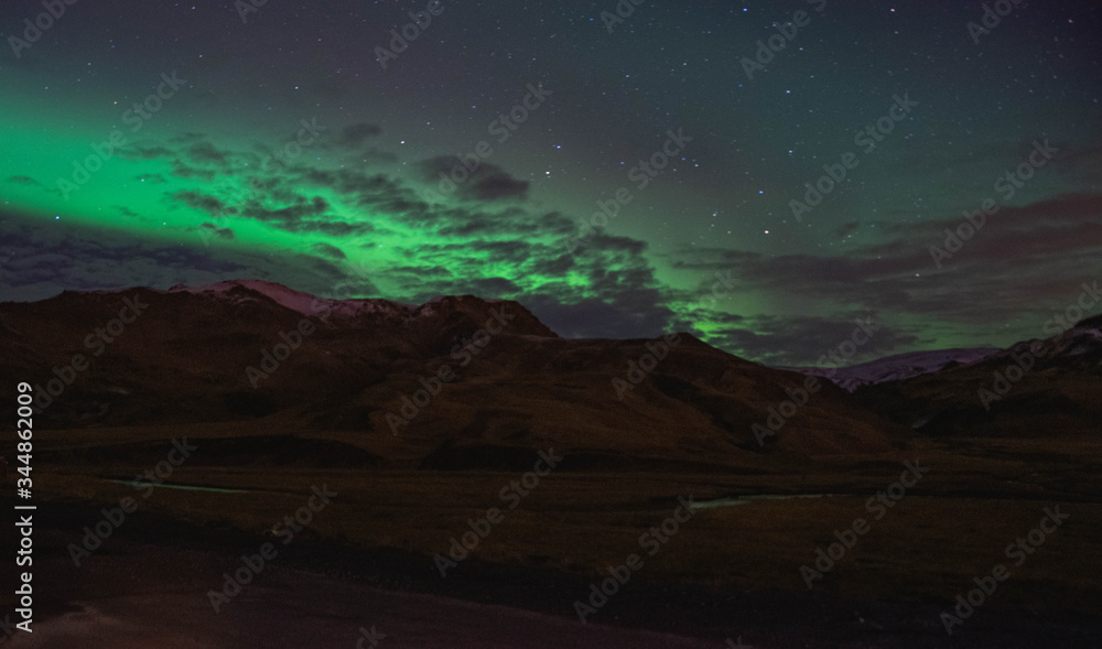 The northern lights lighting up the sky above Icelandic mountains.