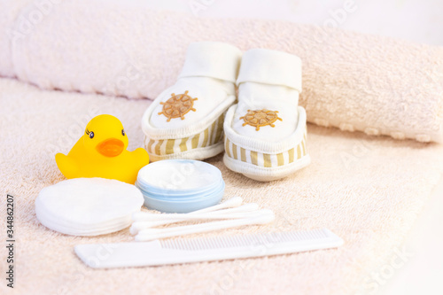 baby hygiene and bath items, shampoo bottle, baby soap, towel, yellow duck rubber toy, cotton pads and ear sticks, comb.