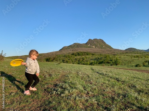 A girl of three years old plays in nature. Cheerful little beautiful girl on the grass. Happy little kid in the fresh air.