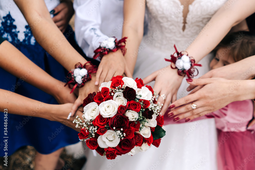 Wedding bouquet hands of the bride bridesmaids with white, red yellow roses and greenery beige background Wedding bouquet hands of the bride bridesmaids with white, red yellow roses and greenery beige background