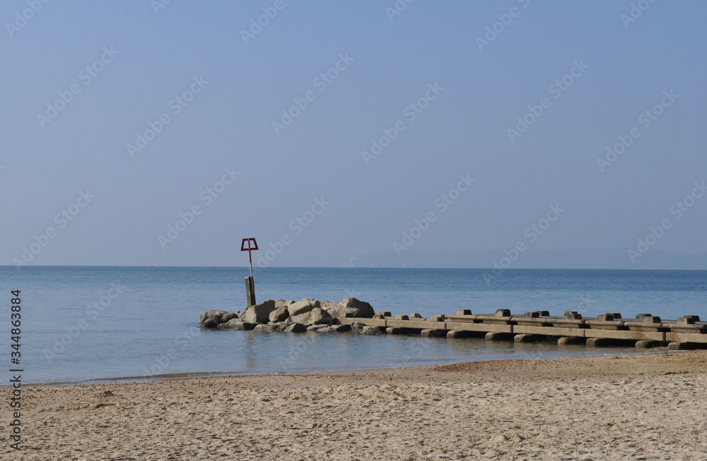 A concrete groyne stretching out into a calm Atlantic ocean from Bournemouth Beach.