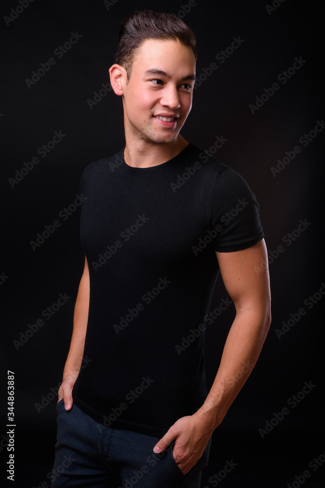 Fototapeta premium Young handsome multi ethnic man against black background