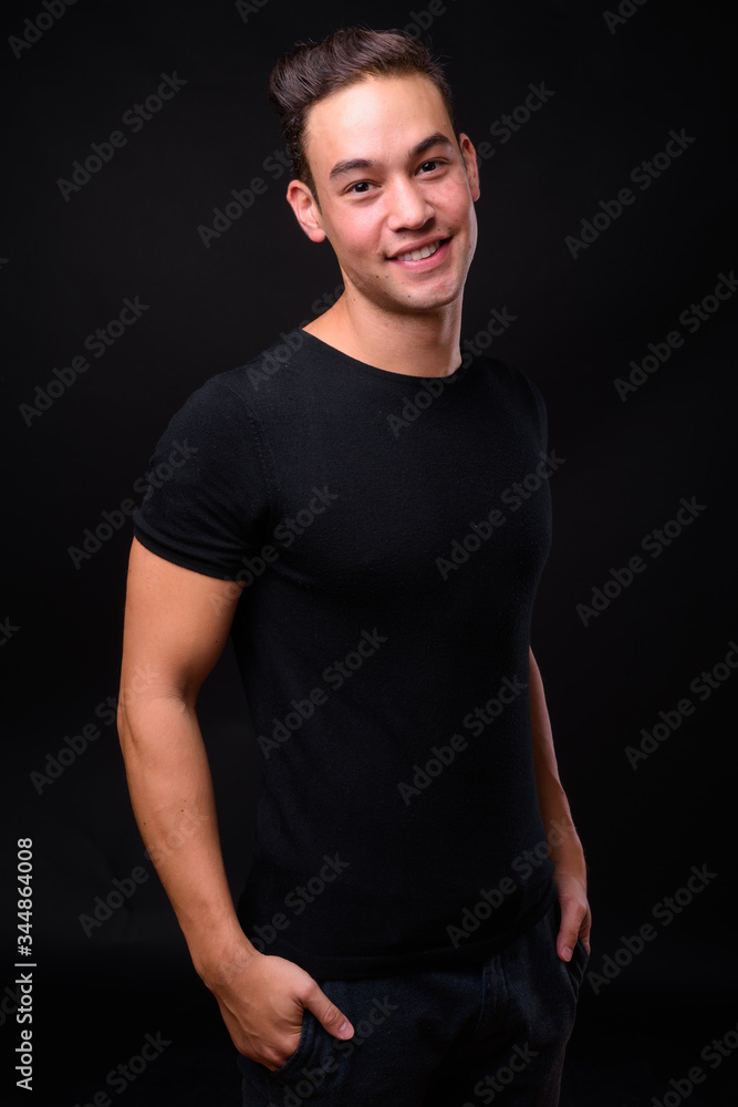 Fototapeta premium Young handsome multi ethnic man against black background
