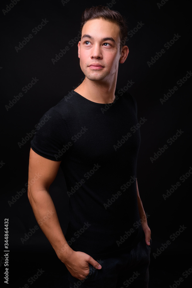 Young handsome multi ethnic man against black background Young handsome multi ethnic man against black background