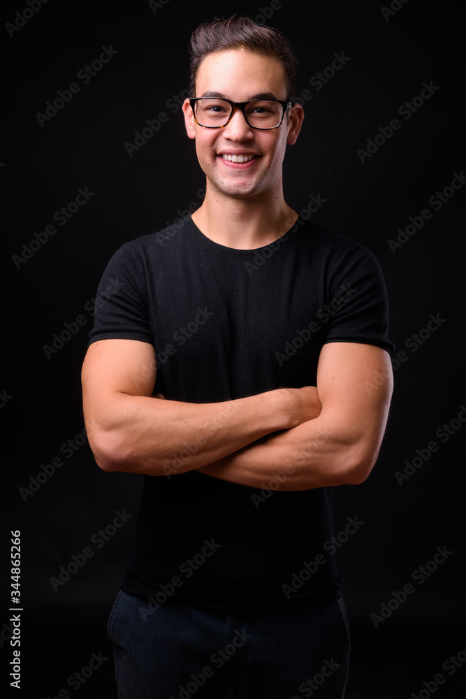 Young handsome multi ethnic man against black background Young handsome multi ethnic man against black background