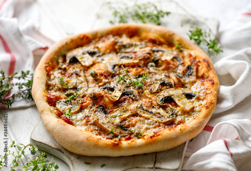 Mushroom pizza with parmesan cheese and herbs on a white board close up