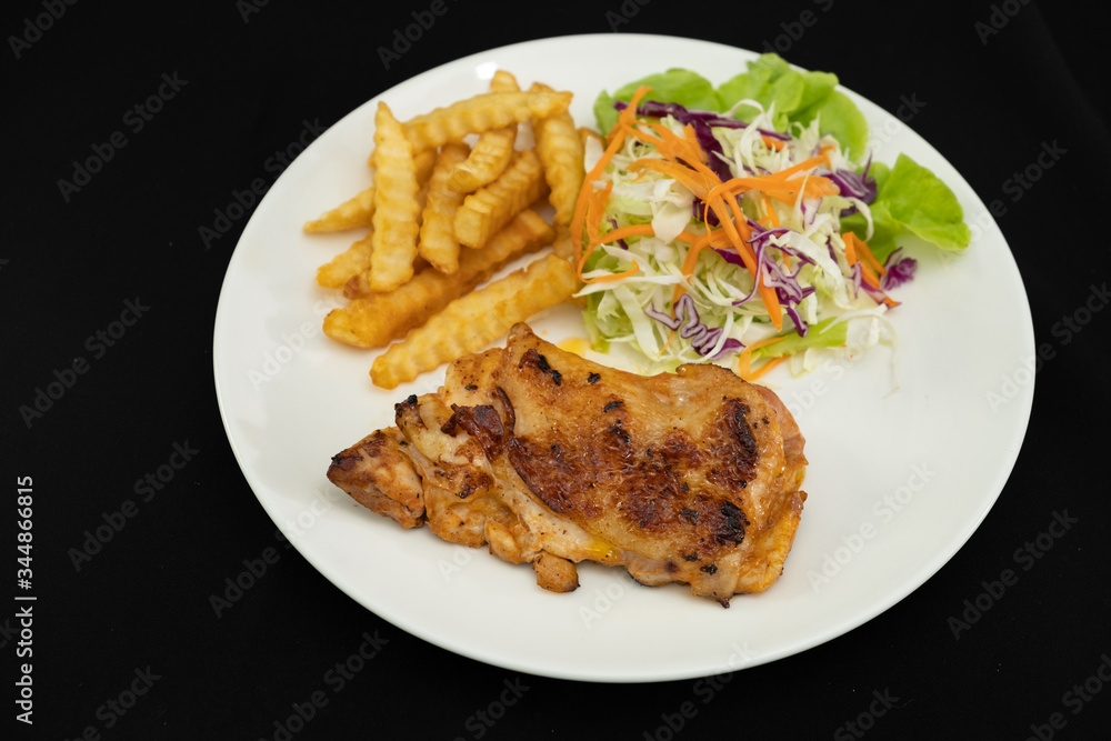Plate of grilled chicken with french fries and vegetables on dark background- Stock photo Plate of grilled chicken with french fries and vegetables on dark background- Stock photo