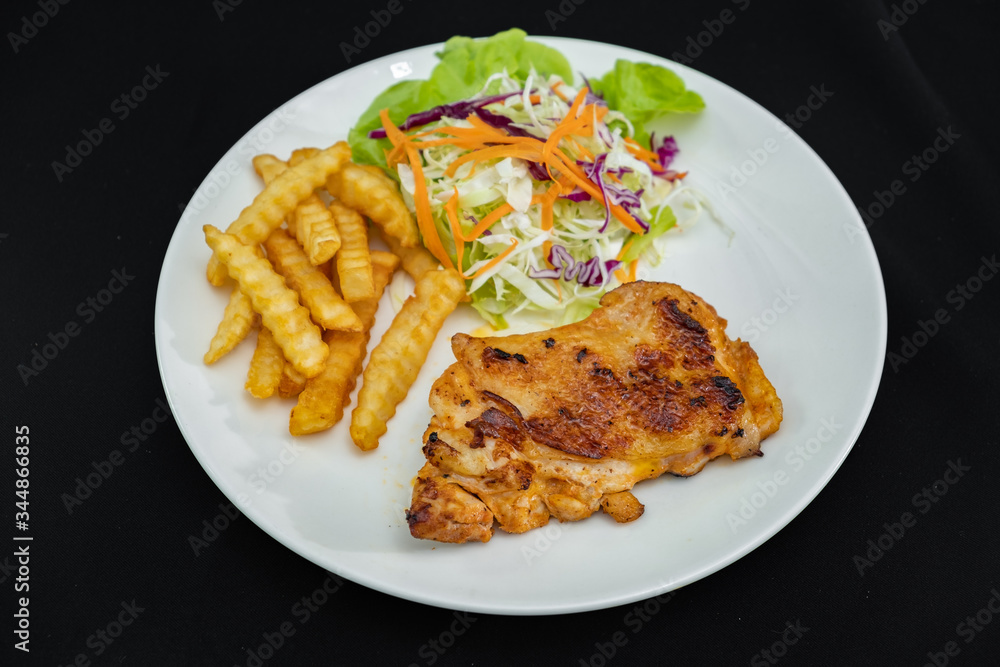 Plate of grilled chicken with french fries and vegetables on dark background- Stock photo Plate of grilled chicken with french fries and vegetables on dark background- Stock photo