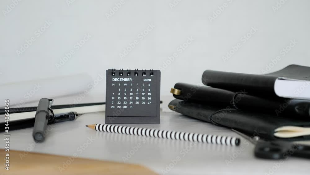 Man hand put small black calendar on office desk. December month 2020 Year. Man hand put small black calendar on office desk. December month 2020 Year.