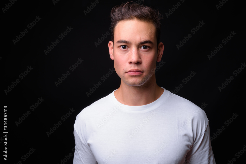 Young handsome multi ethnic man against black background Young handsome multi ethnic man against black background
