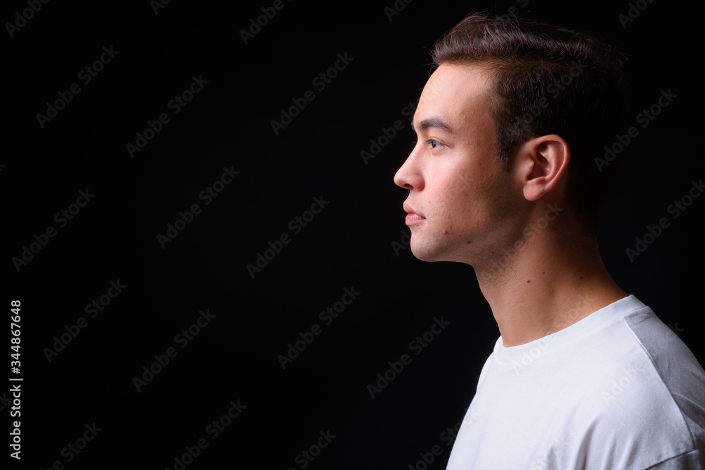 Young handsome multi ethnic man against black background Young handsome multi ethnic man against black background