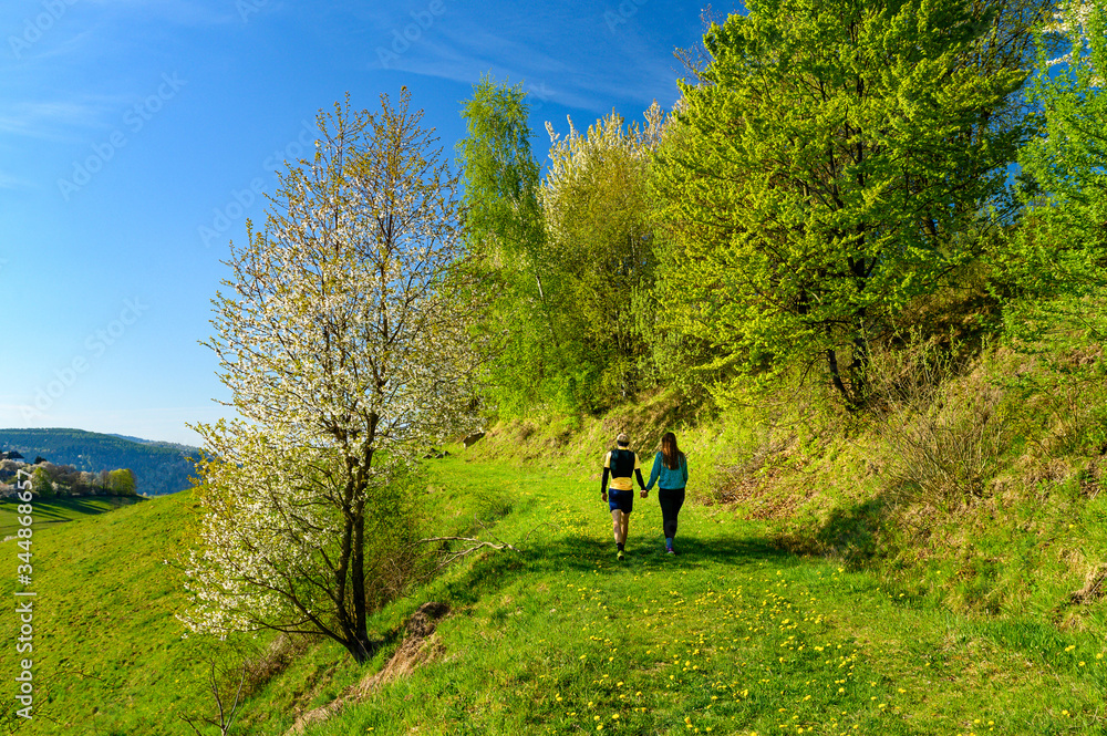 Man and woman in love walking together in green spring blossom nature Man and woman in love walking together in green spring blossom nature