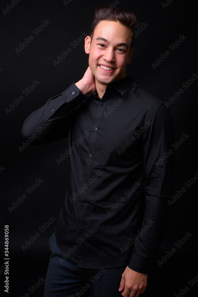 Fototapeta premium Young handsome multi ethnic businessman against black background