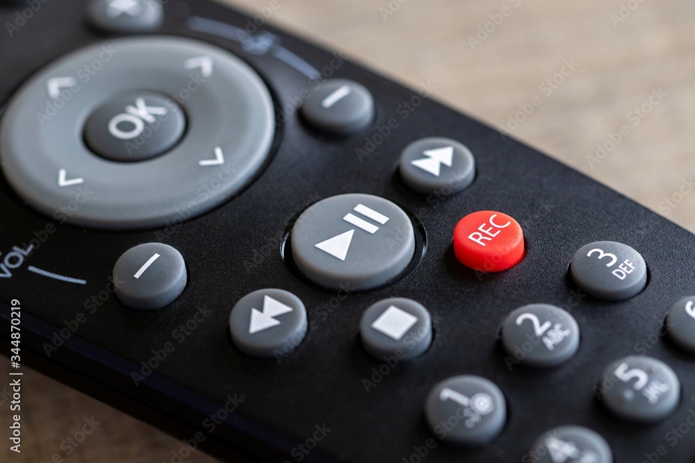 A close up portrait of a remote control to operate a surround sound system, television or other electronic device. The focus is on the play/pause, stop, record and fast forward and rewind buttons. A close up portrait of a remote control to operate a surround sound system, television or other electronic device. The focus is on the play/pause, stop, record and fast forward and rewind buttons.