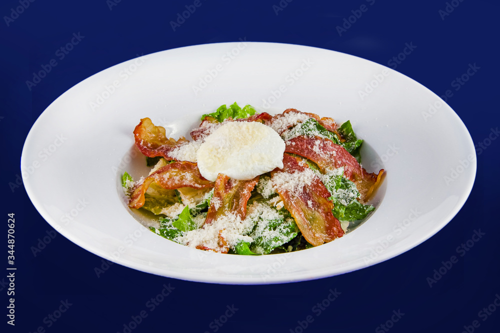 Salad with fragrant breadcrumbs, bacon, parmesan and fresh leaves lettuce, dressed with soft cheese. Closeup on a white plate on a blue background. Salad with fragrant breadcrumbs, bacon, parmesan and fresh leaves lettuce, dressed with soft cheese. Closeup on a white plate on a blue background.
